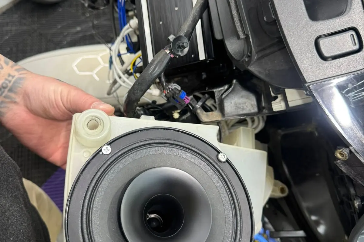 A speaker being fitted into a vehicle door at Mr. Tint, the door card off