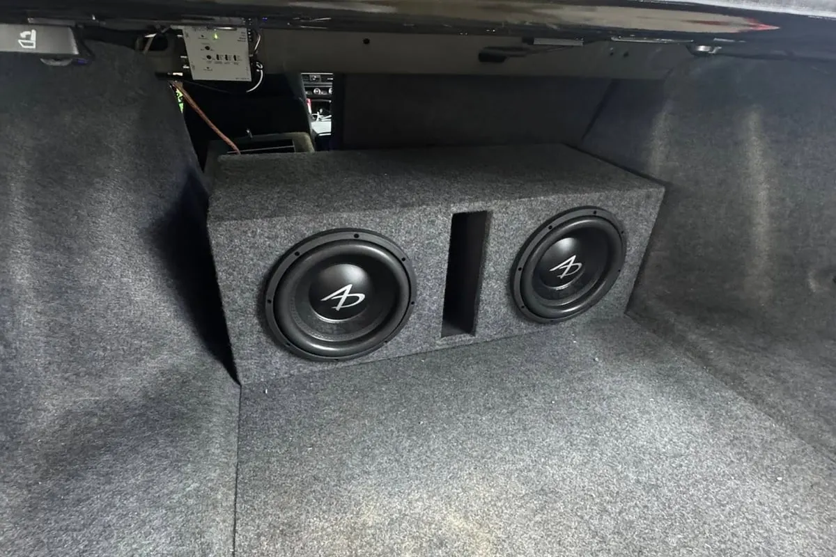 Two subwoofers in a carpeted enclosure fitted under the rear deck of a car at Mr. Tint