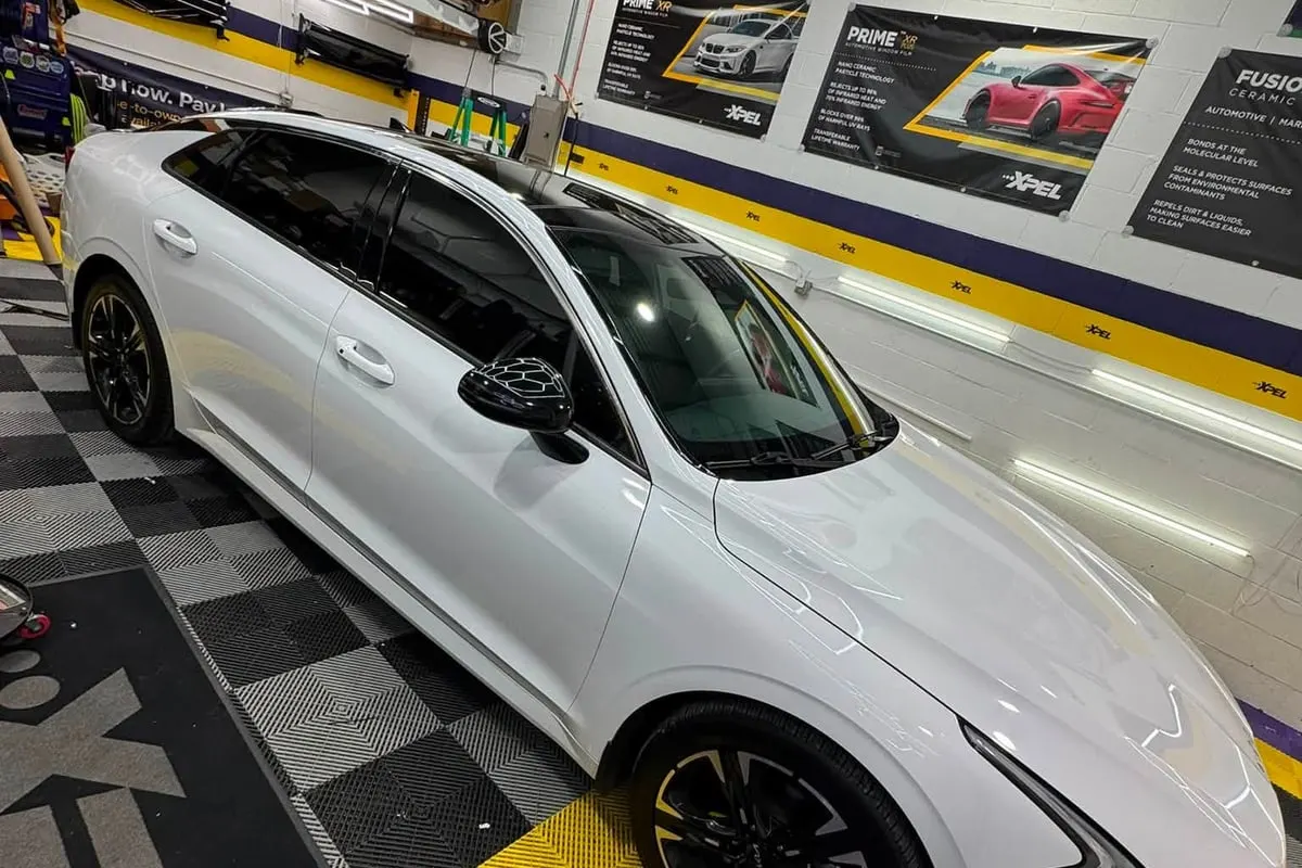 A white Kia K5 with tinted windows at Mr. Tint