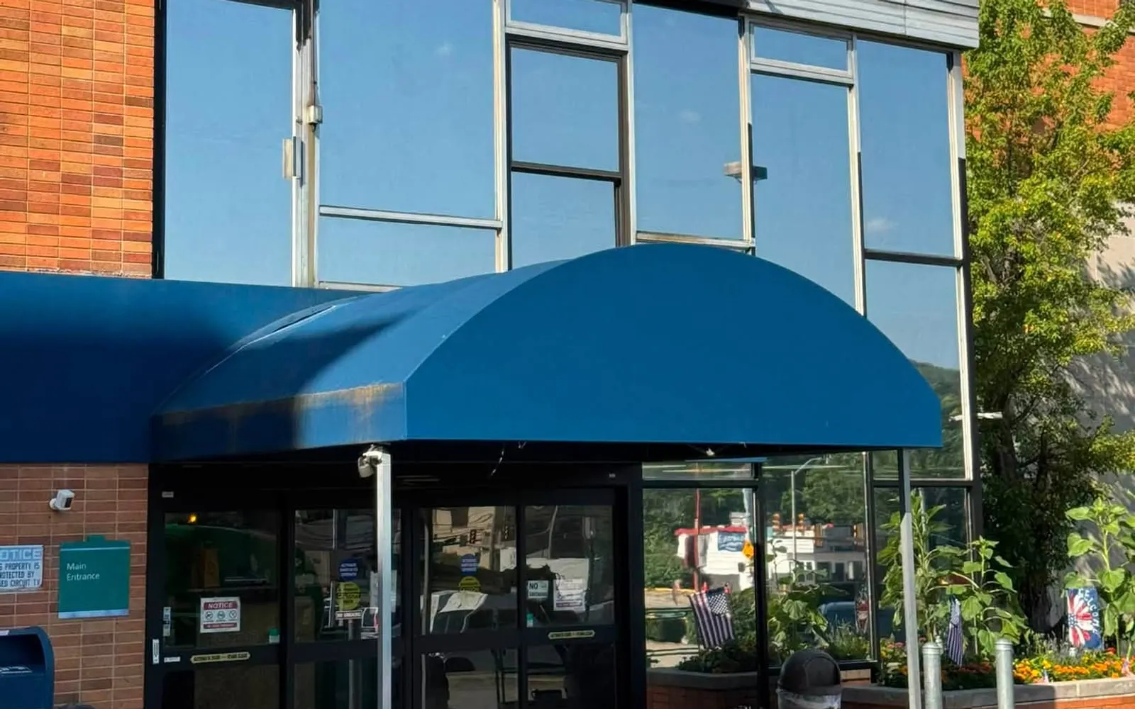 A Pittsburgh storefront with filmed glazing, a blue awning and glass entrance doors