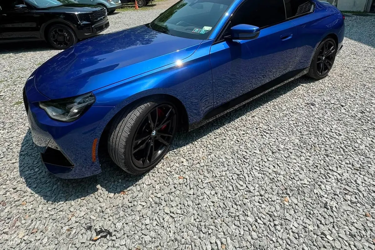 A blue Infiniti Q50 with ceramic window tint on the gravel at Mr. Tint