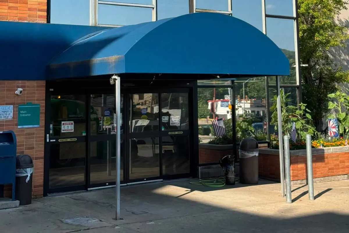 The entrance of a brick commercial building with tinted glazing under a blue awning
