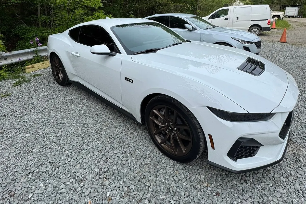 A white Ford Mustang coupe on the gravel lot at Mr. Tint after ceramic coating