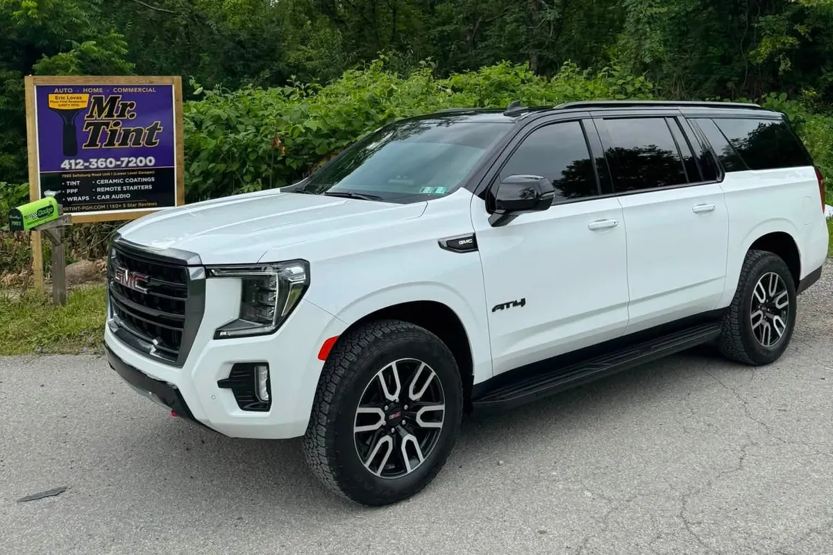 A white GMC Yukon beside the Mr. Tint road sign in Plum, Pennsylvania