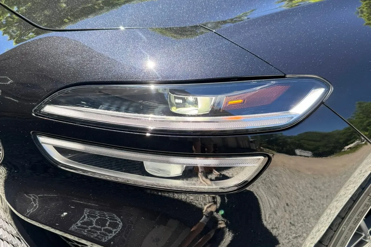 A close view of a dark vehicle's front bumper and headlight covered with clear paint protection film