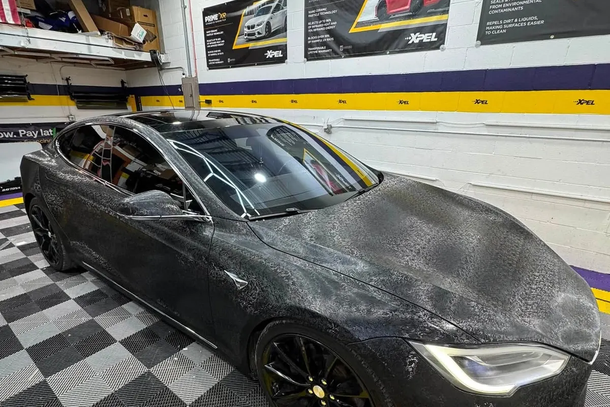 A Tesla Model S wrapped in forged carbon, seen from the front corner at Mr. Tint