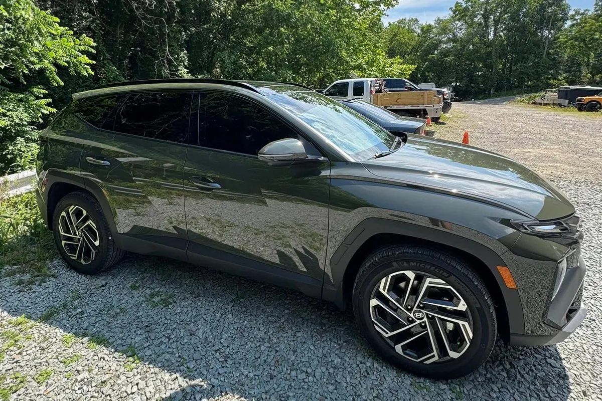 A dark green wrapped SUV on the gravel lot at Mr. Tint