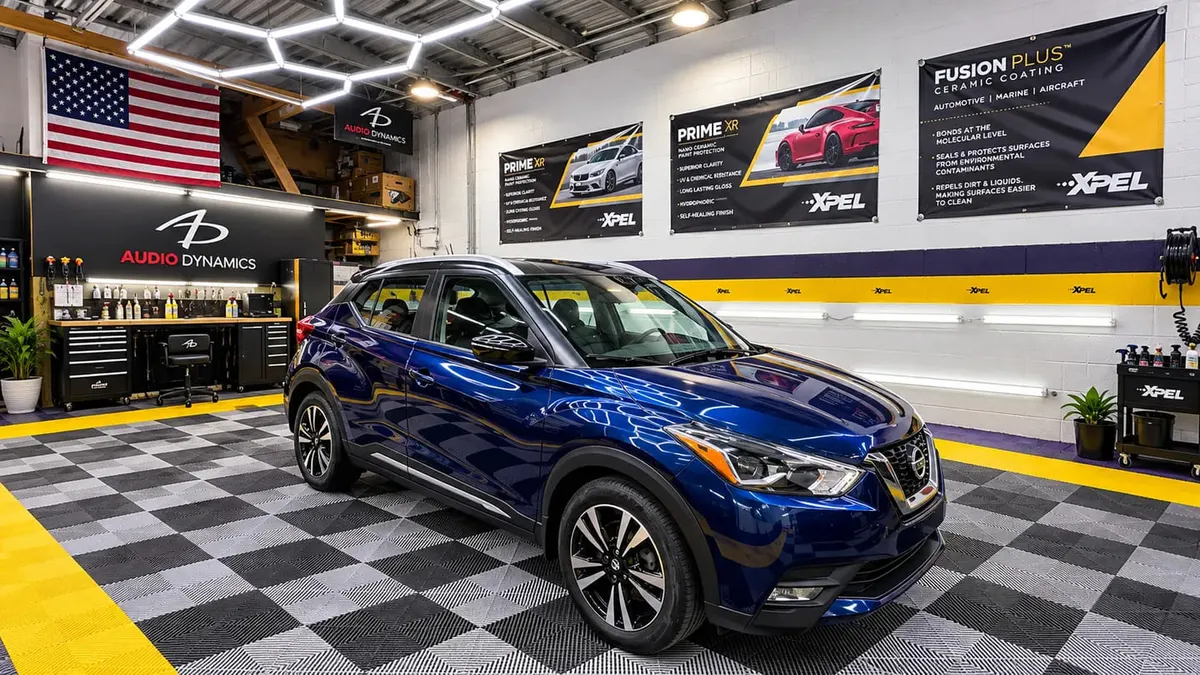 A blue crossover in the hexagon-lit installation bay at Mr. Tint in Plum, Pennsylvania, with XPEL film and ceramic coating displays on the wall behind it