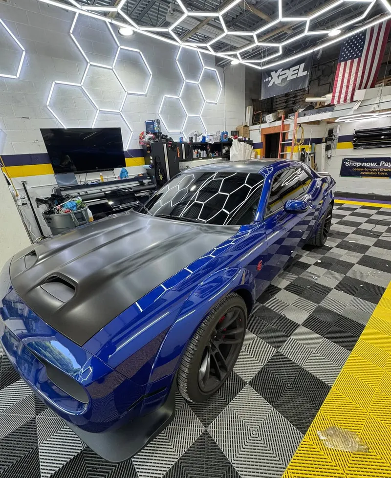 A vehicle under the hexagon lighting of the Mr. Tint installation bay
