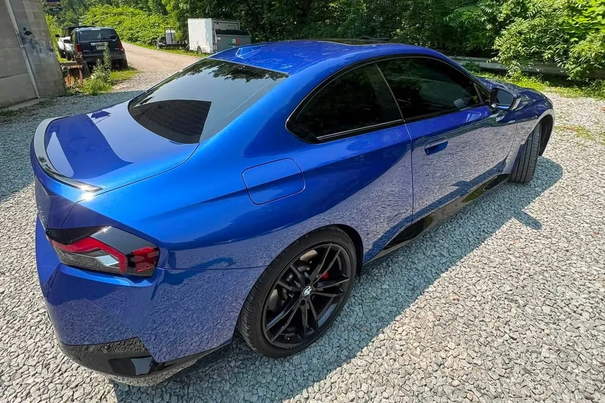 A coupe finished in a blue colour-change wrap, seen from the rear three-quarter