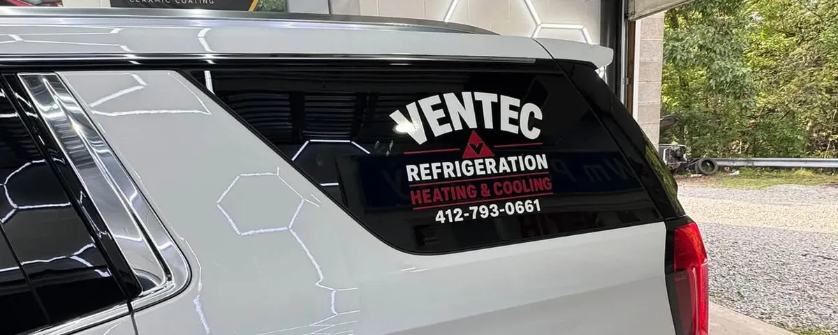 Cut vinyl lettering for a heating and cooling company applied to the rear glass of a white fleet SUV