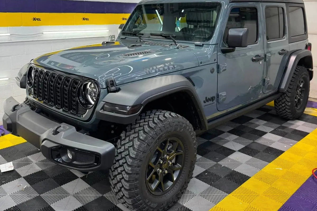 A Jeep Wrangler in the Mr. Tint installation bay, seen from the front three-quarter