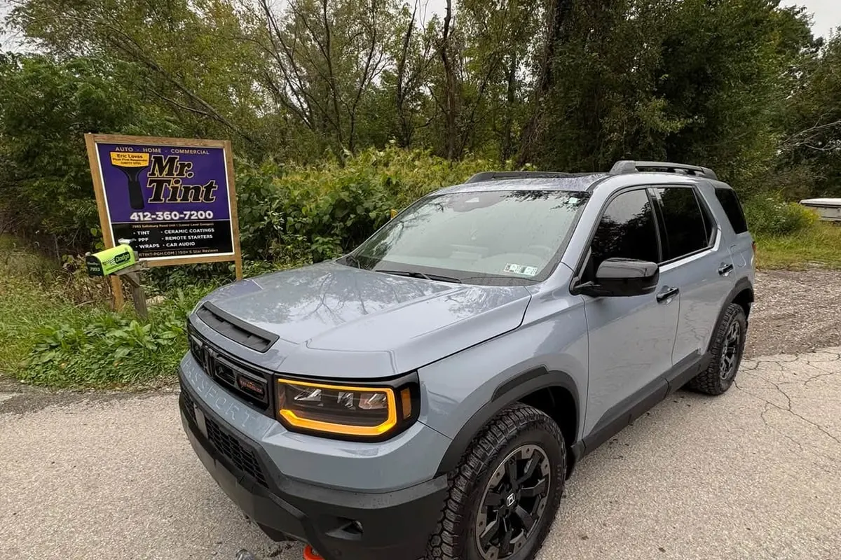 A grey SUV with paint protection film beside the Mr. Tint road sign in Plum, Pennsylvania