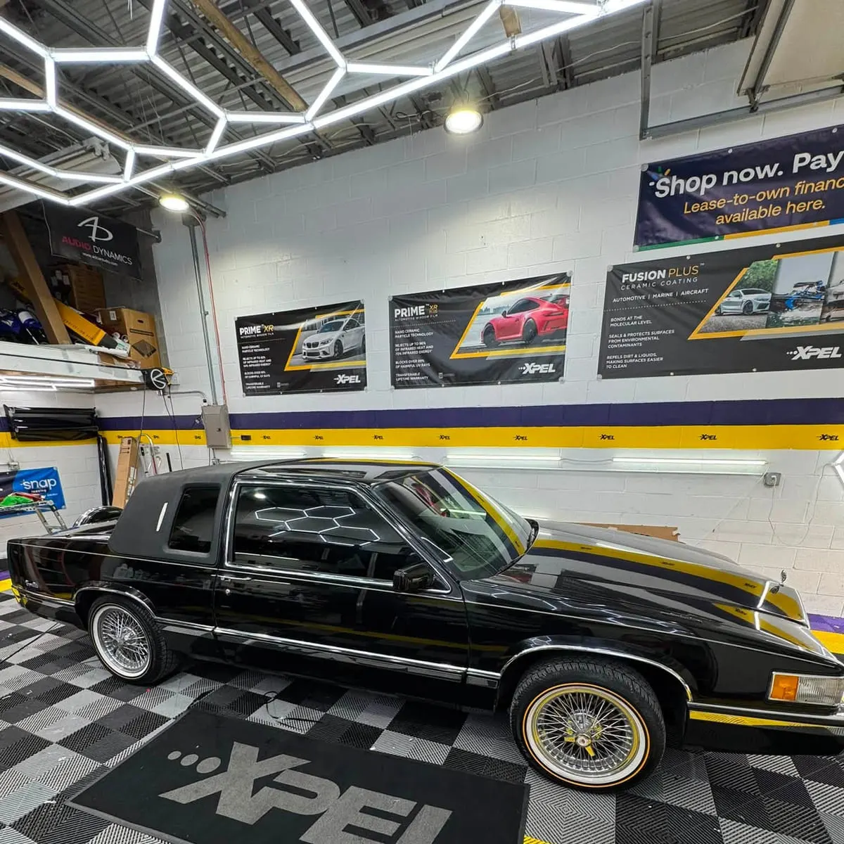 A classic Cadillac on the XPEL-branded floor of the Mr. Tint installation bay in Plum