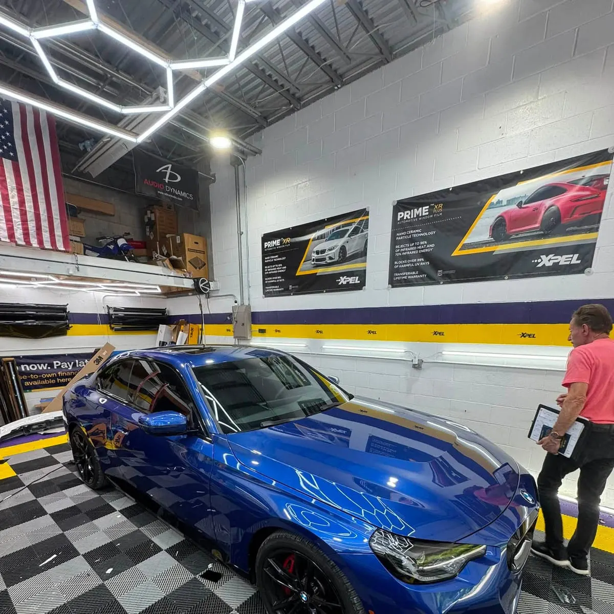 A blue colour-change wrap being fitted to a coupe in the Mr. Tint installation bay
