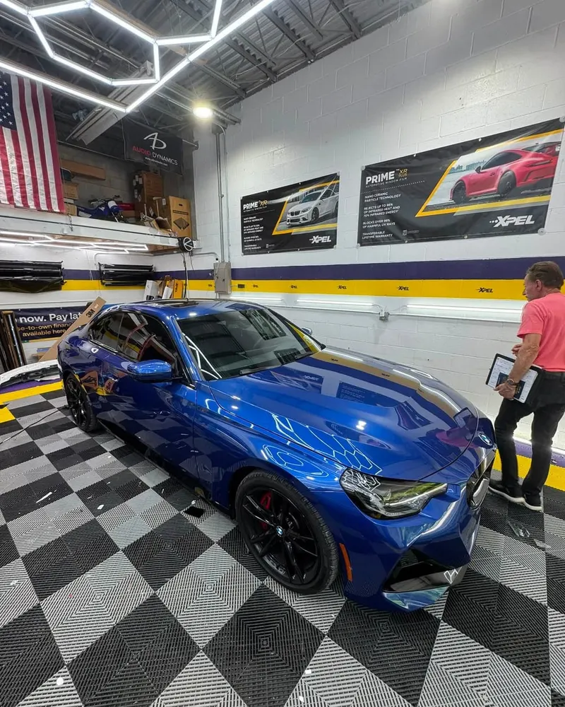 A member of the Mr. Tint team working beside a car in the Plum installation bay