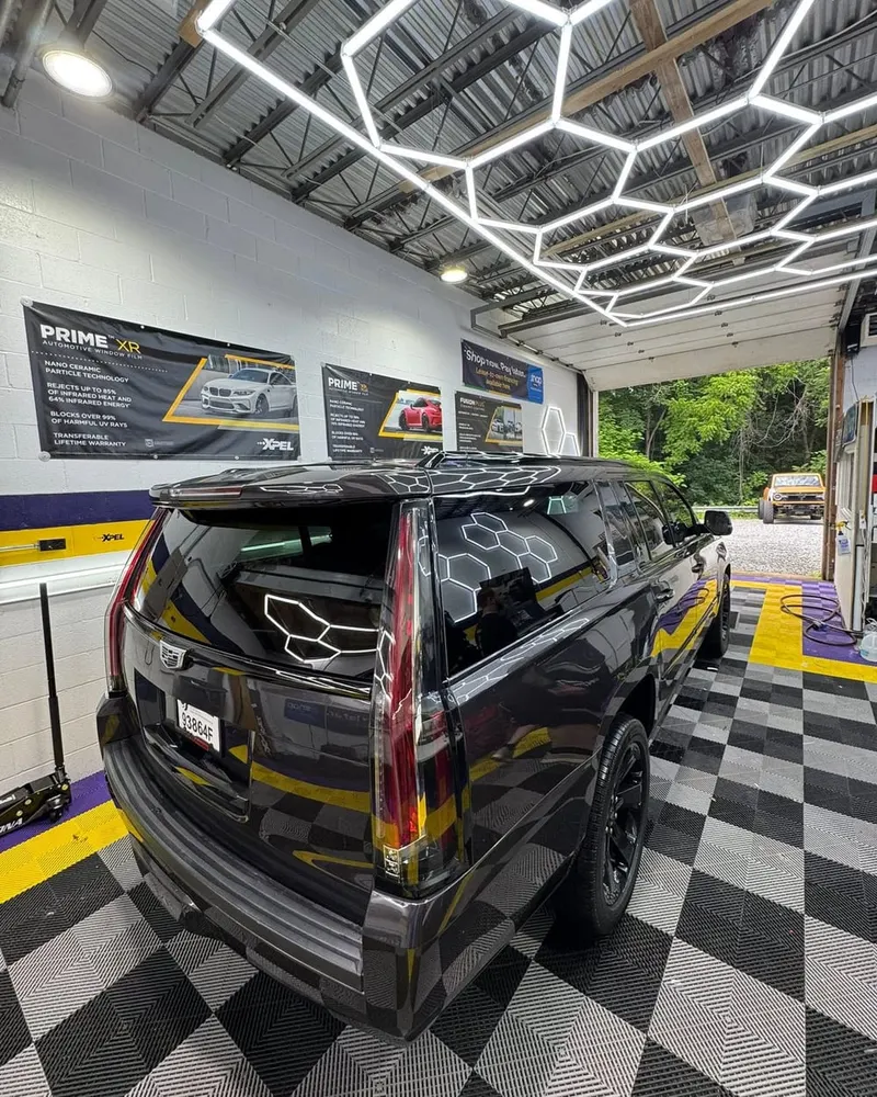A black SUV with tinted glass under the hexagon lighting in the Mr. Tint installation bay