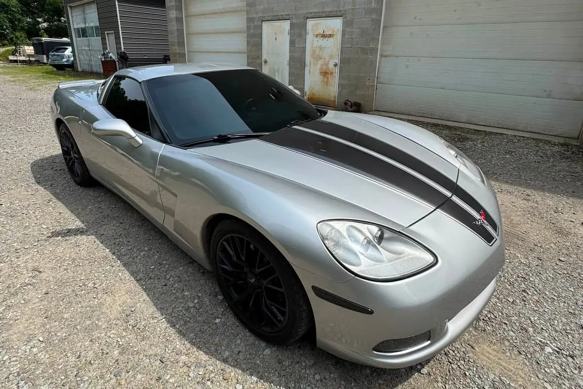 A silver sports car with contrasting vinyl stripes down the bonnet and roof