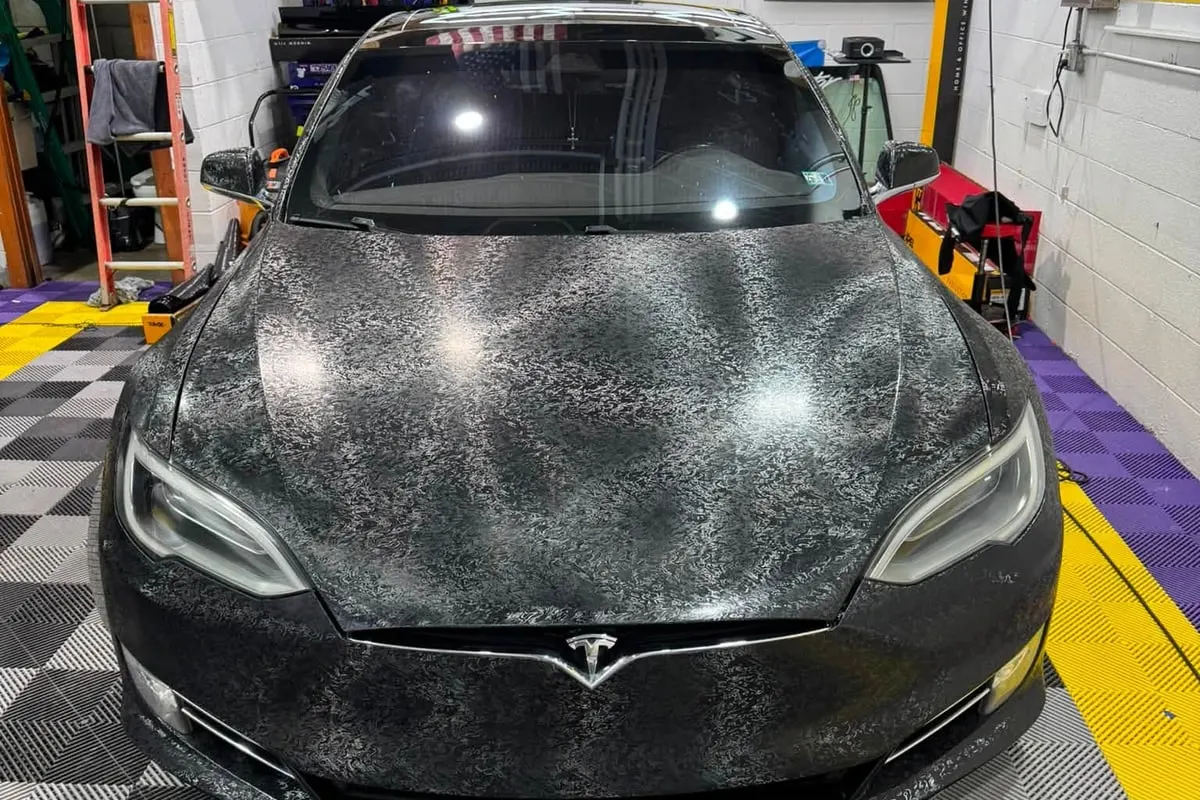 A Tesla Model S wrapped in forged carbon, seen from the front at Mr. Tint